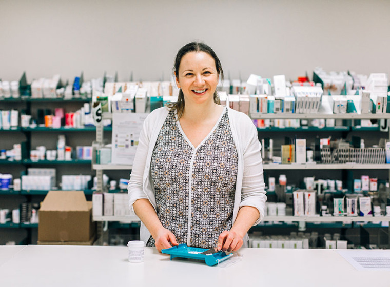 Pharmacist standing at a table with a medication counter