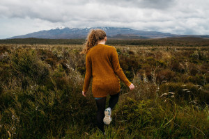 Woman walking through tundra with mountain in background.