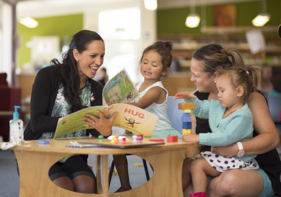 Maori teachers and children reading a book