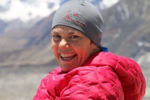 Dr Jan Bone, wearing a beanie a bright pink puffer jacket, with a snowy mountain the background